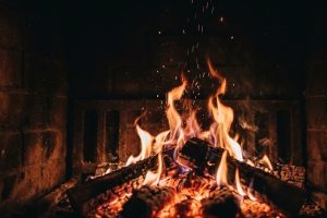 Яркое пламя в камине с искрами в полумраке