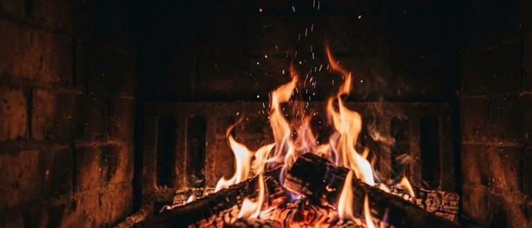 Яркое пламя в камине с искрами в полумраке